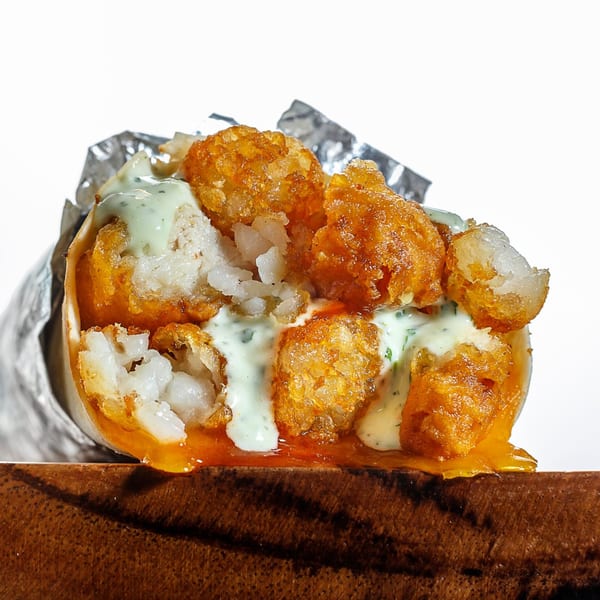 A Sweeto Burrito with crispy tater tots, white fish, and creamy green sauce, wrapped in foil.