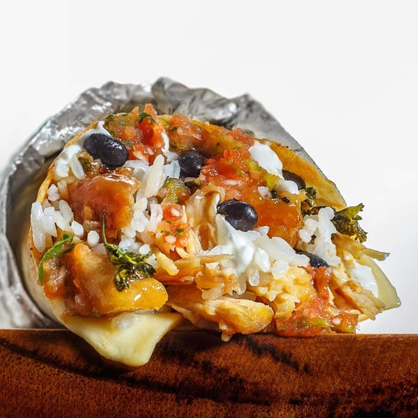 A cross-section of a Sweeto Burrito, revealing rice, black beans, salsa, and melted cheese.