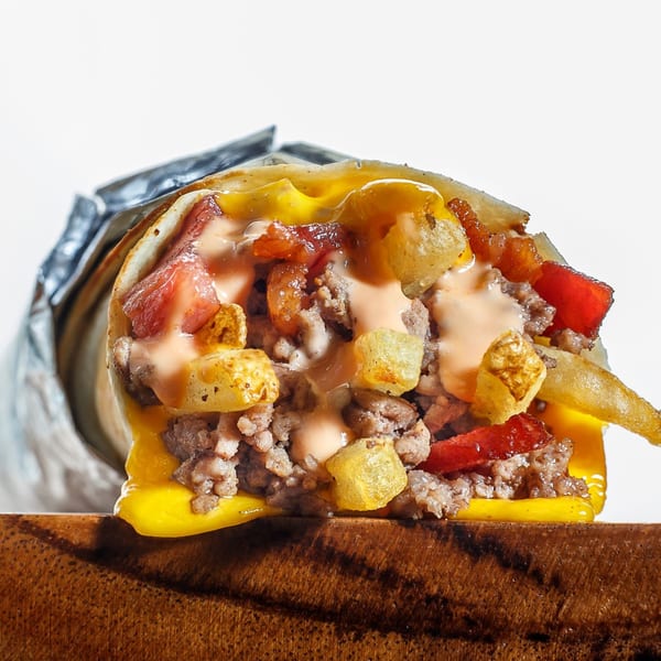 A Sweeto Burrito filled with ground meat, cheese, fries, and sauce, wrapped in foil.