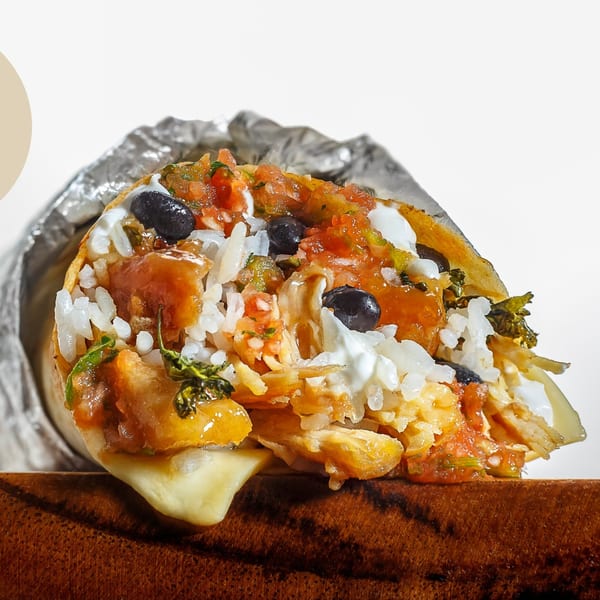 A Sweeto Burrito, cut open, revealing rice, black beans, salsa, and melted cheese.