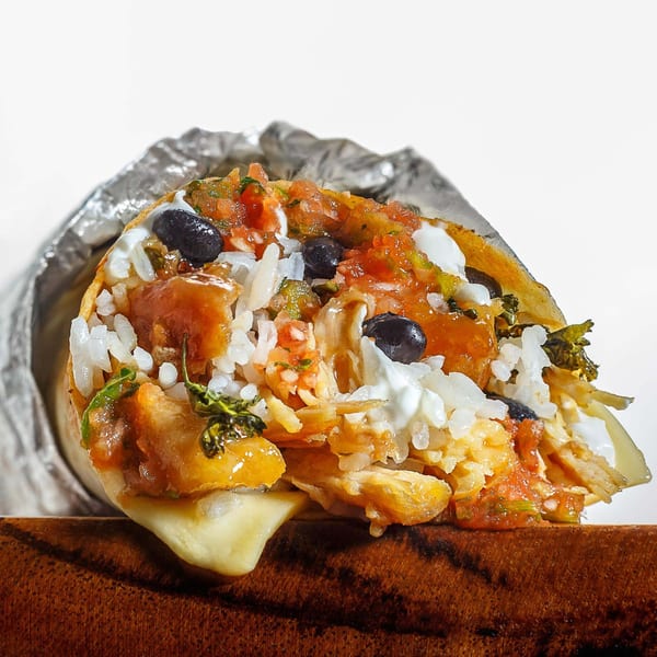 A Sweeto Burrito, cut open, revealing rice, black beans, salsa, and sour cream.