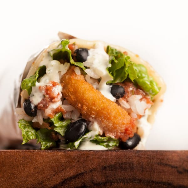 A Sweeto Burrito with a crispy fried stick, black beans, lettuce, rice, and sauce.
