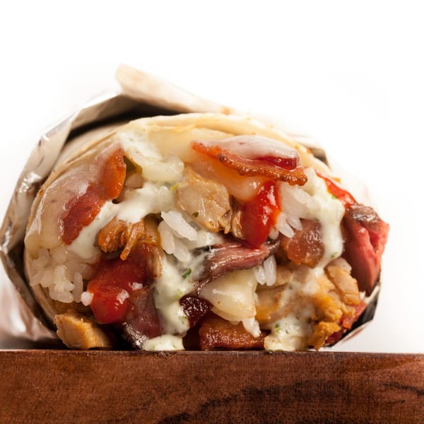 A large, open Sweeto Burrito with visible fillings of meat, rice, and sauces, wrapped in foil.